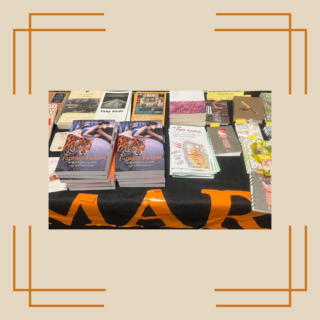 Photo captured of the MAR book sale table at Winter Wheat 2024 framed with a beige background and yellow border