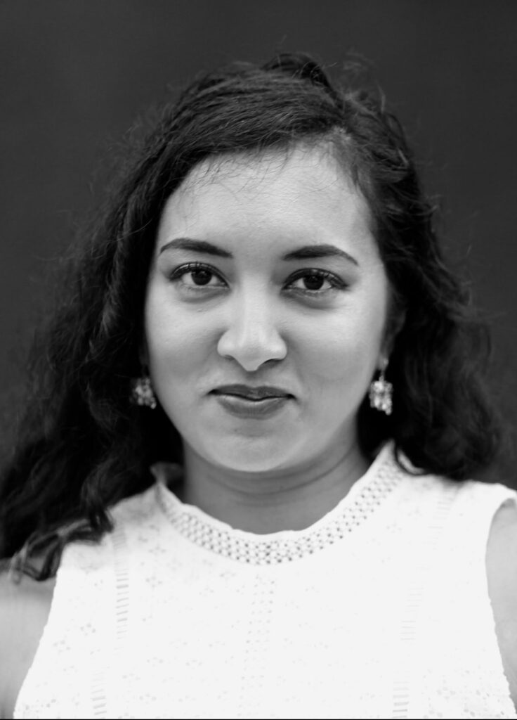 Black-and-white image of a smiling woman with dark hair and white sweater.