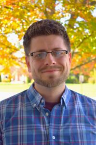 picture of white man with brown hair and glasses, in blue plaid shirt