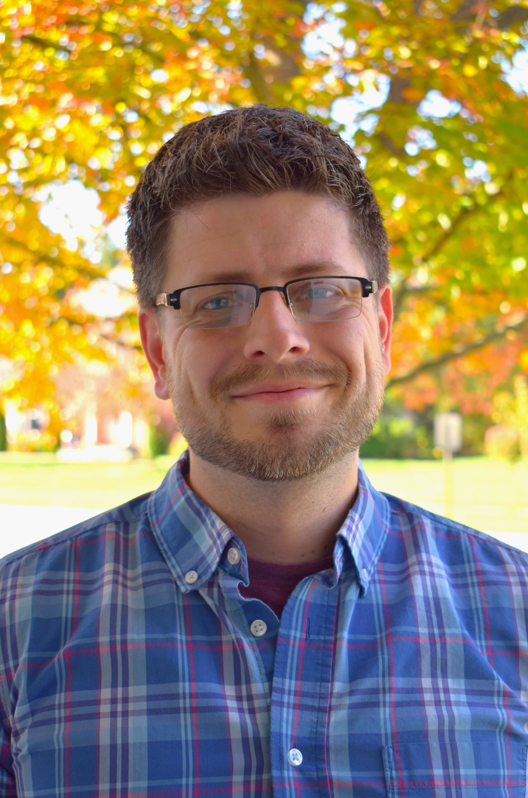 Smiling white man in glasses and blue plaid shirt