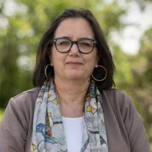 Photo of Paula Lambert, white woman with dark hair, in glasses and earrings